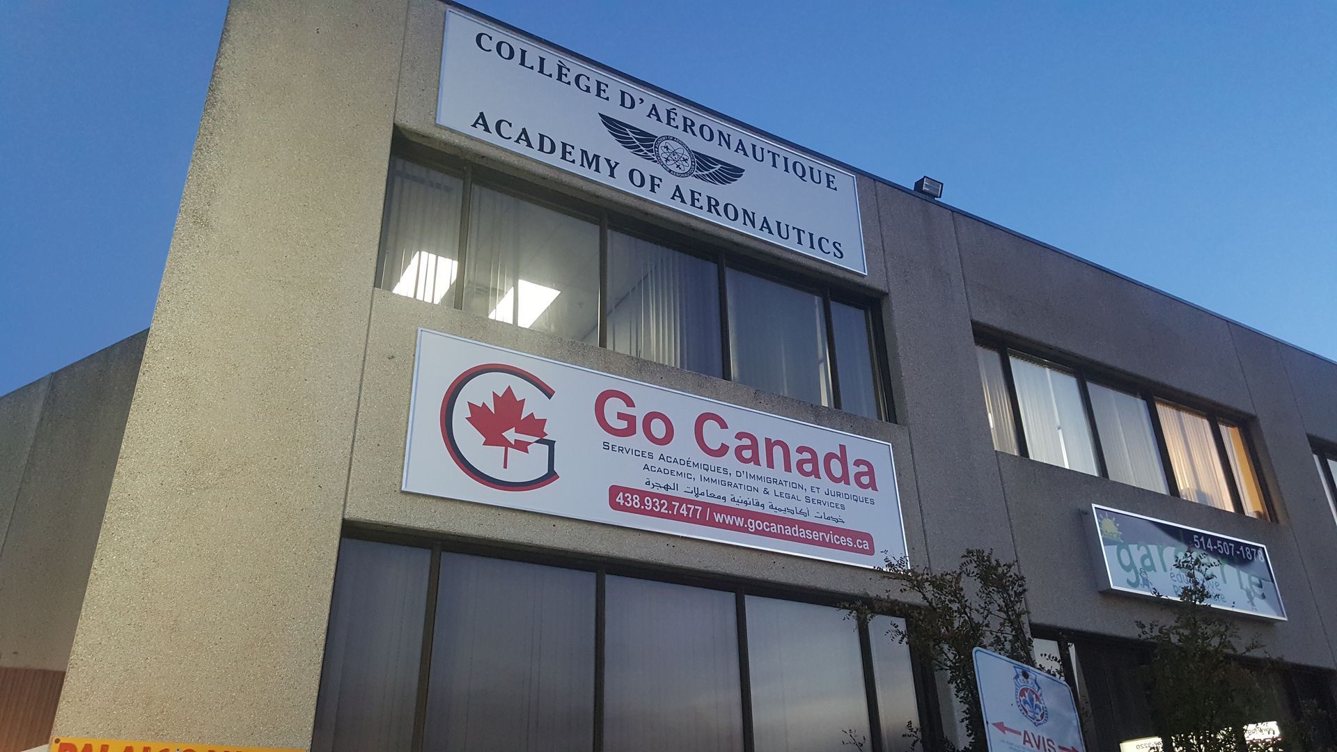 Bâtiment avec des panneaux indiquant « College of Aeronautics » et « Go Canada » au crépuscule.