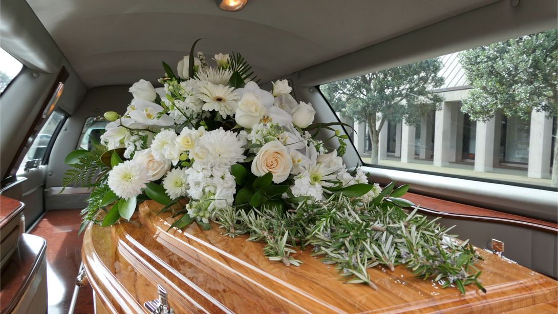 bara con composizione floreale dentro carro funebre