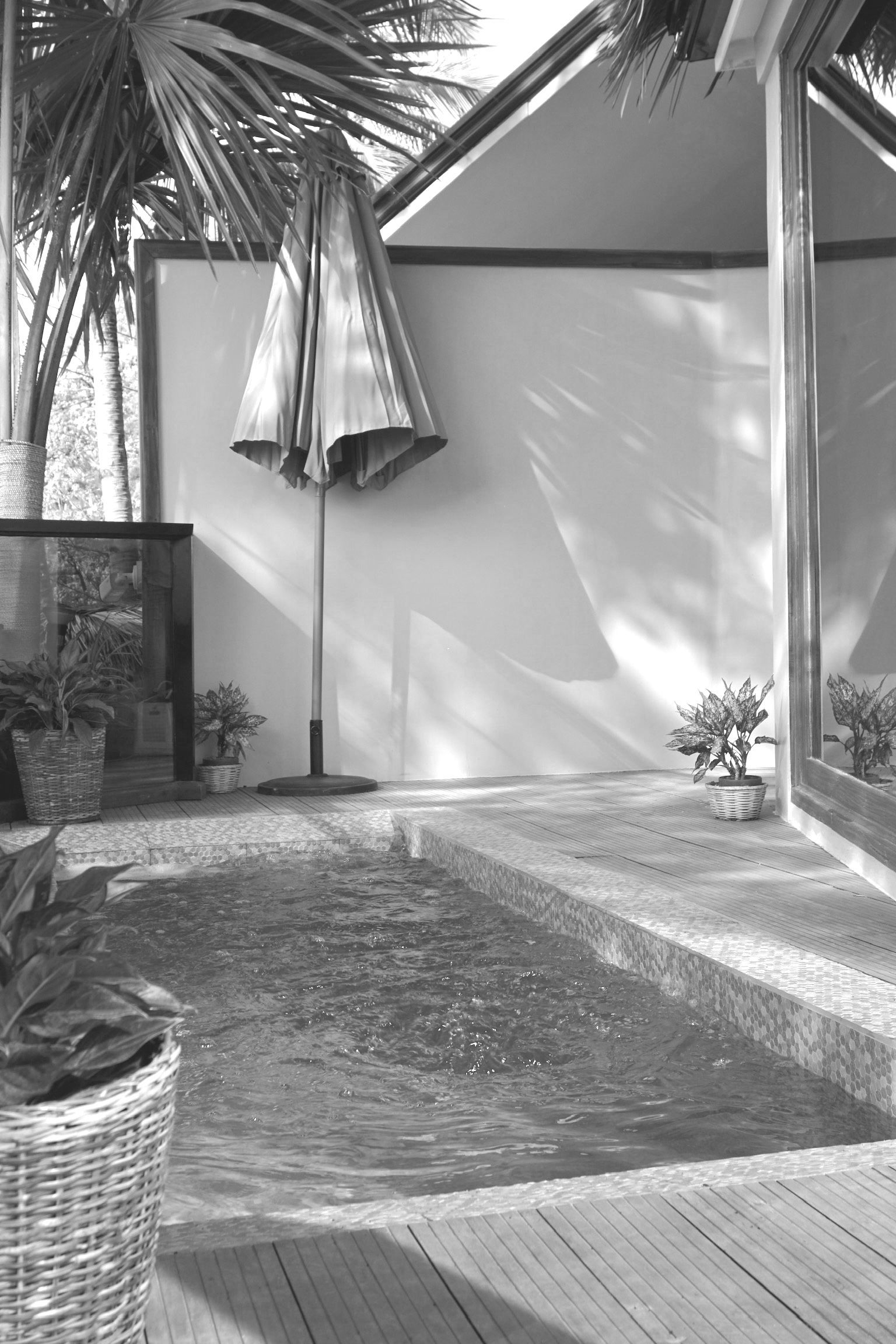 A black and white photo of a pool with an umbrella