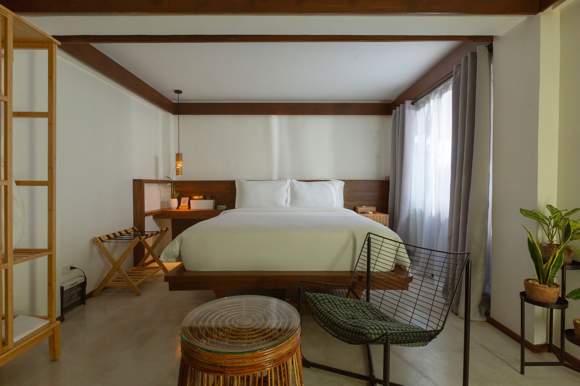 A hotel room with a bed , chair , table and window.