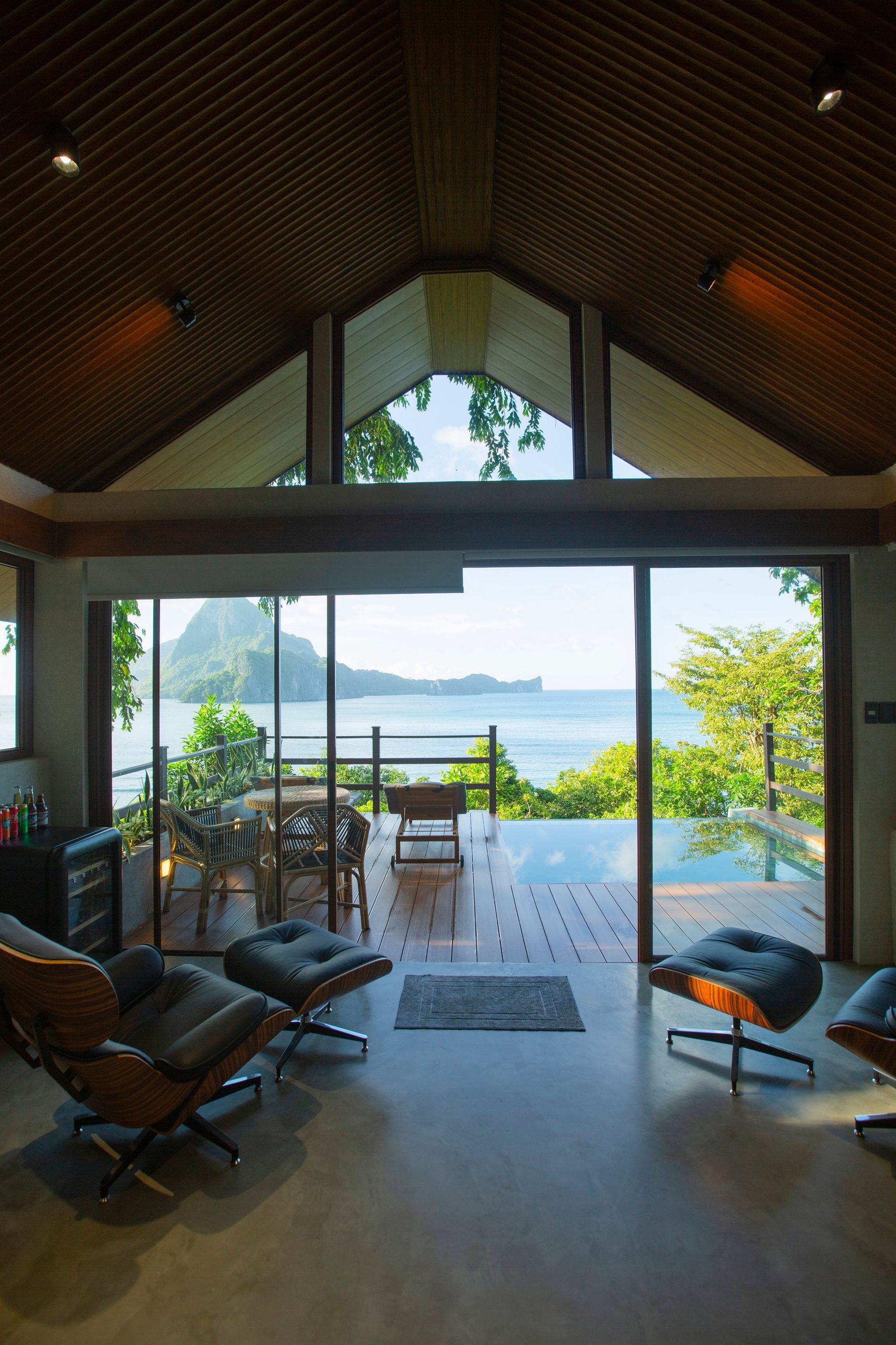 A living room with a view of the ocean and a sliding glass door.