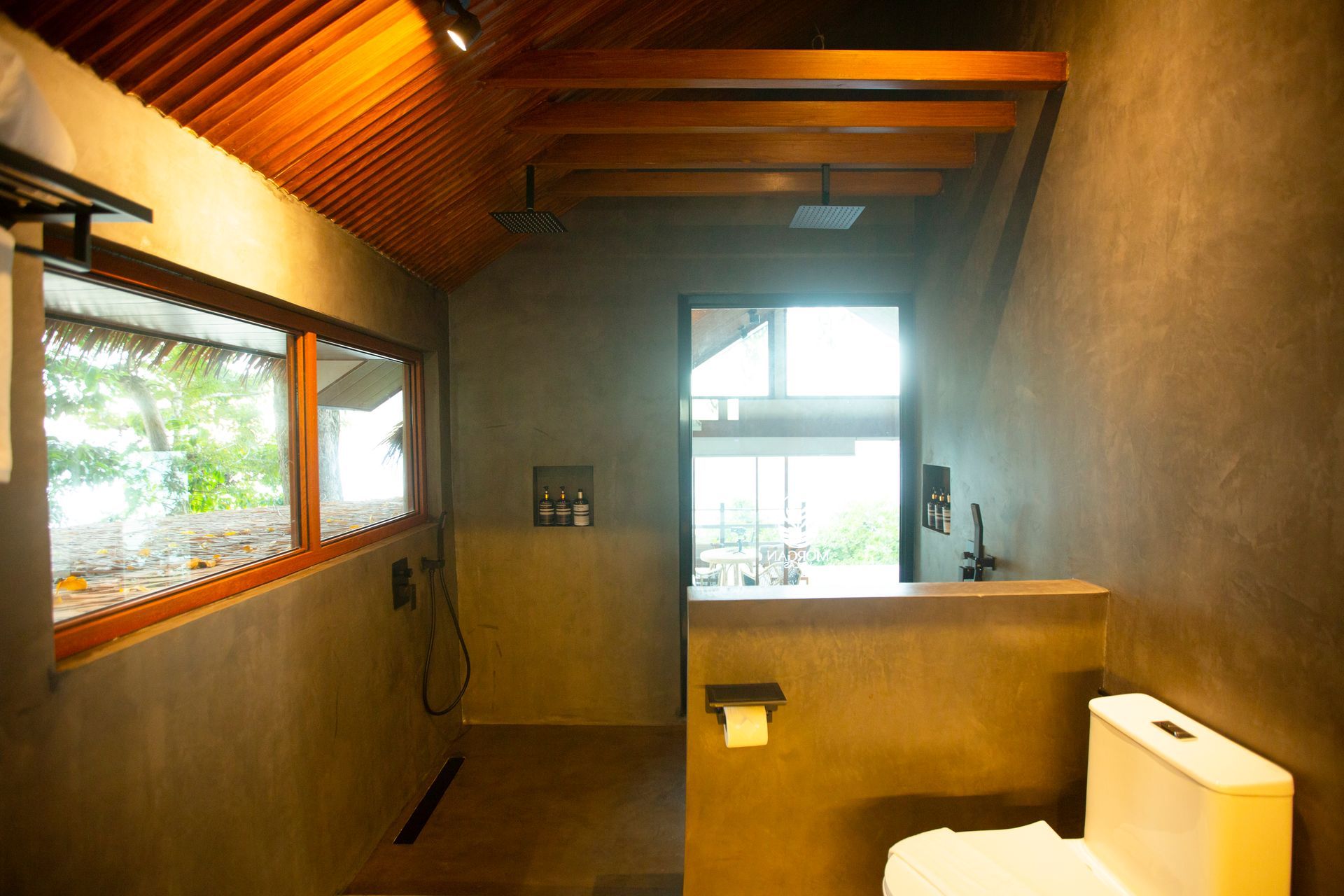 A bathroom with a toilet , shower and window.