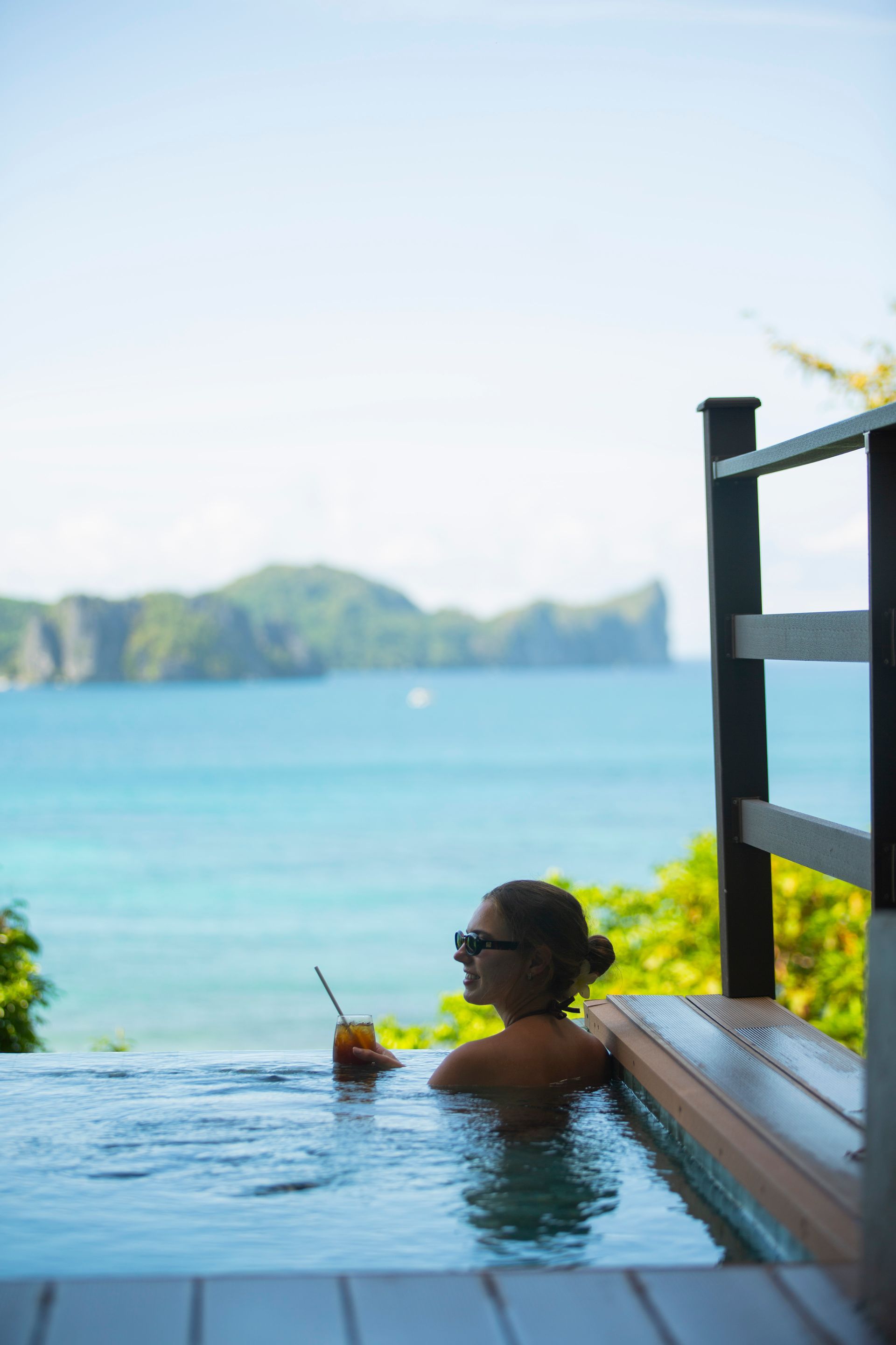 A woman is sitting in a swimming pool with a drink in her hand.