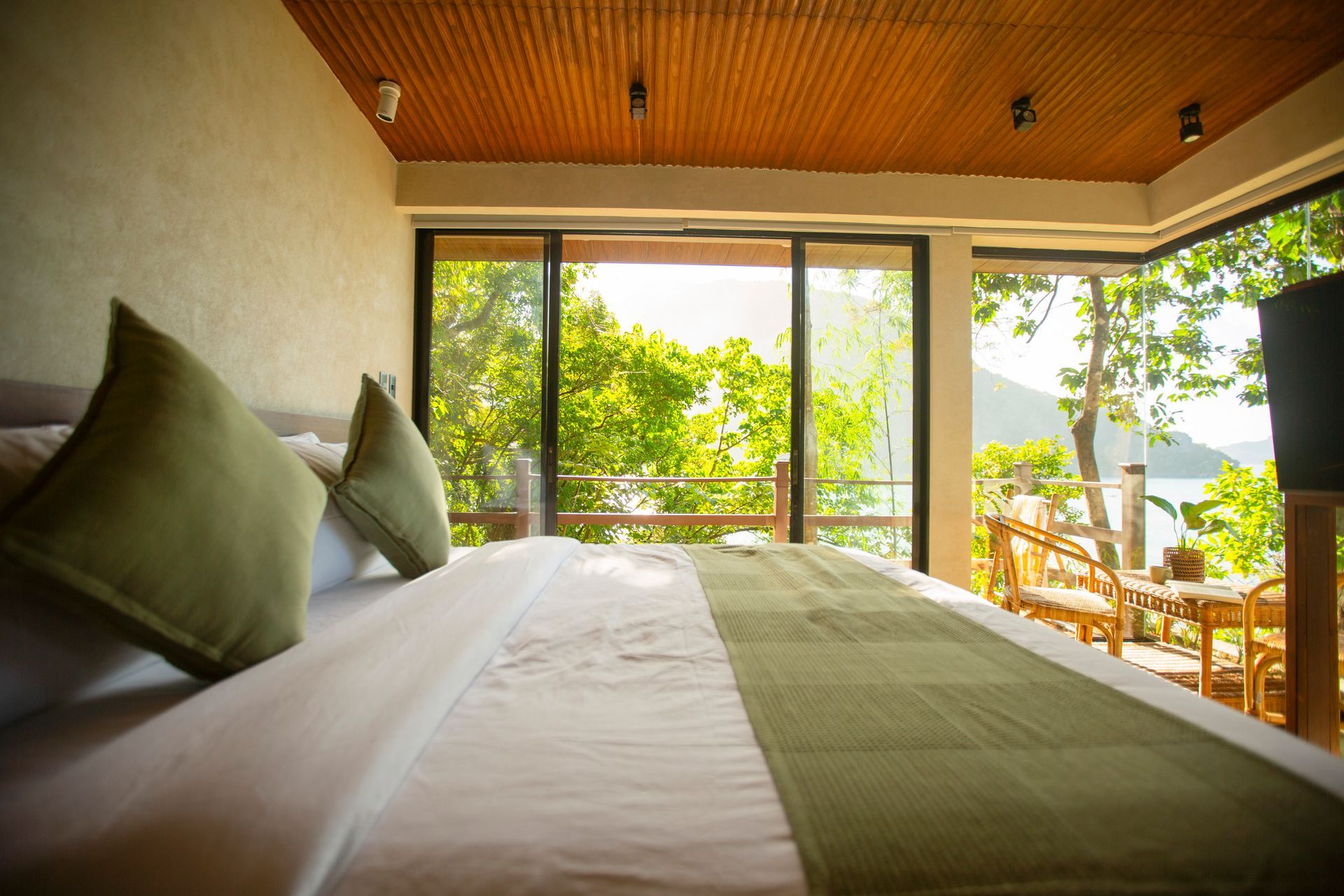 There is a large bed in the middle of the room with a view of the ocean.