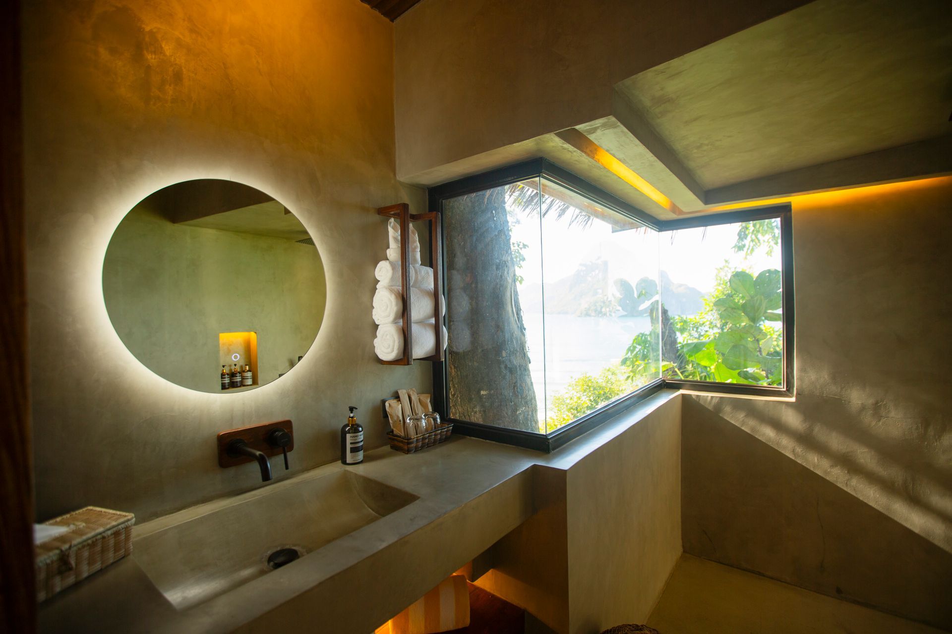 A bathroom with a sink , mirror and window.