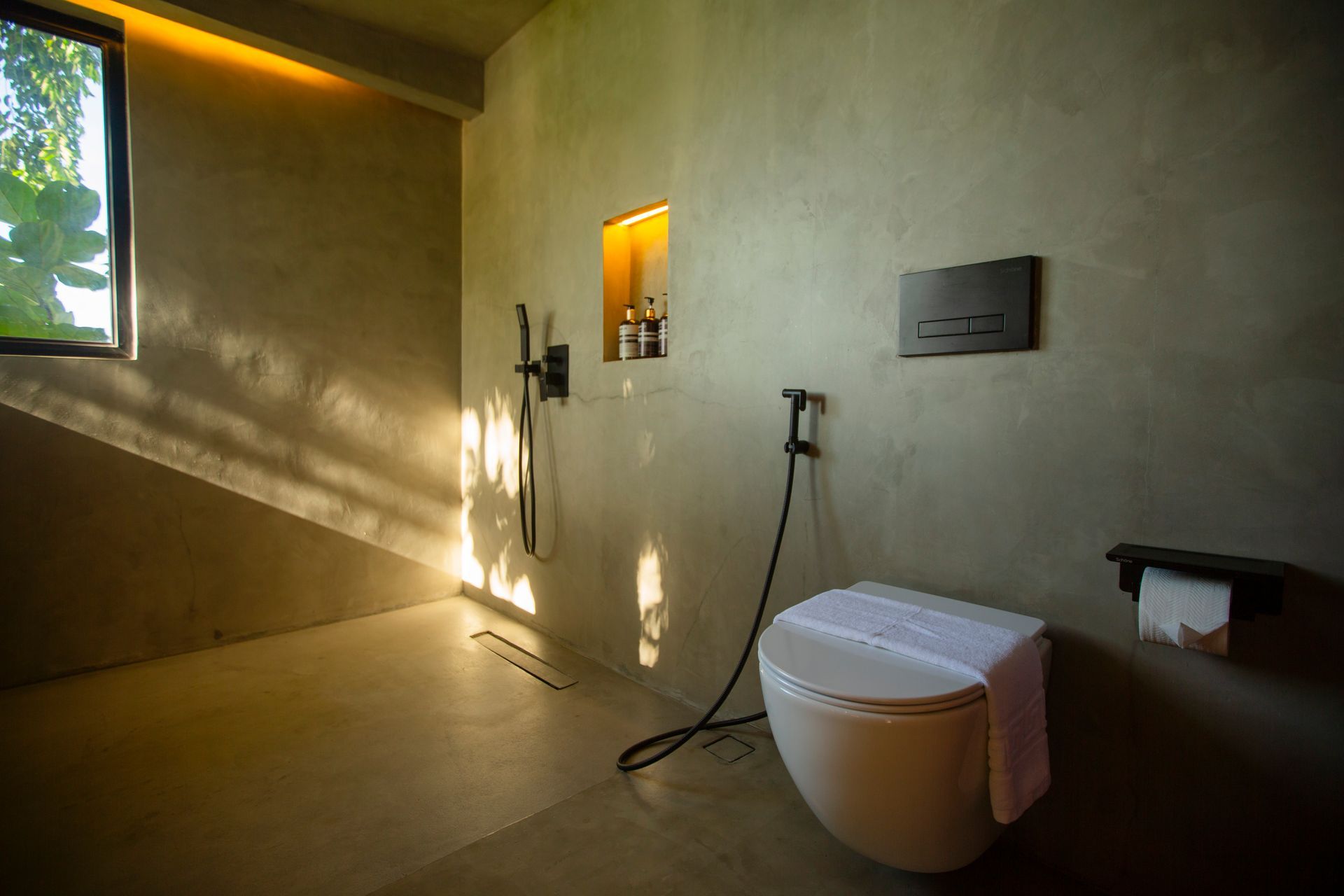 A bathroom with a toilet , shower and window.