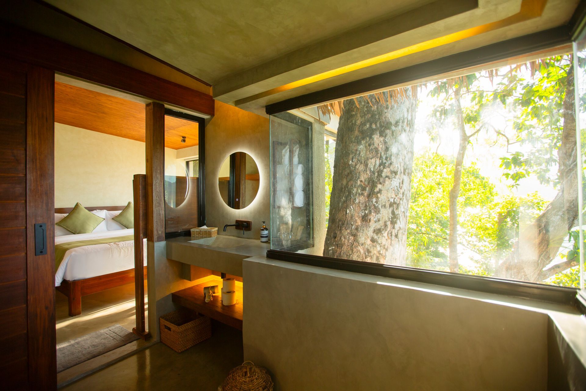 A bathroom with a large window and a tree in the background.