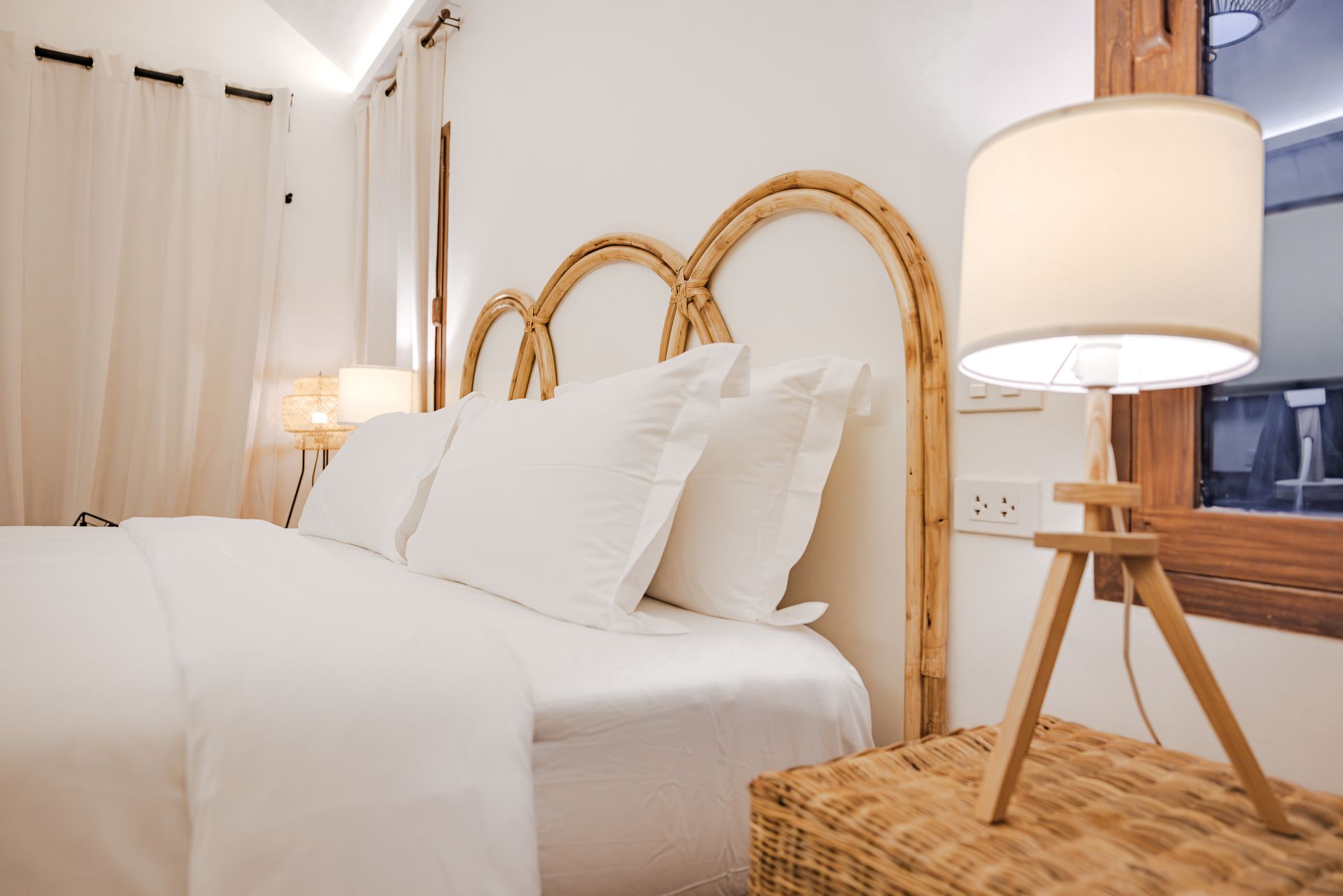 A bedroom with a wicker headboard and a lamp on a nightstand.