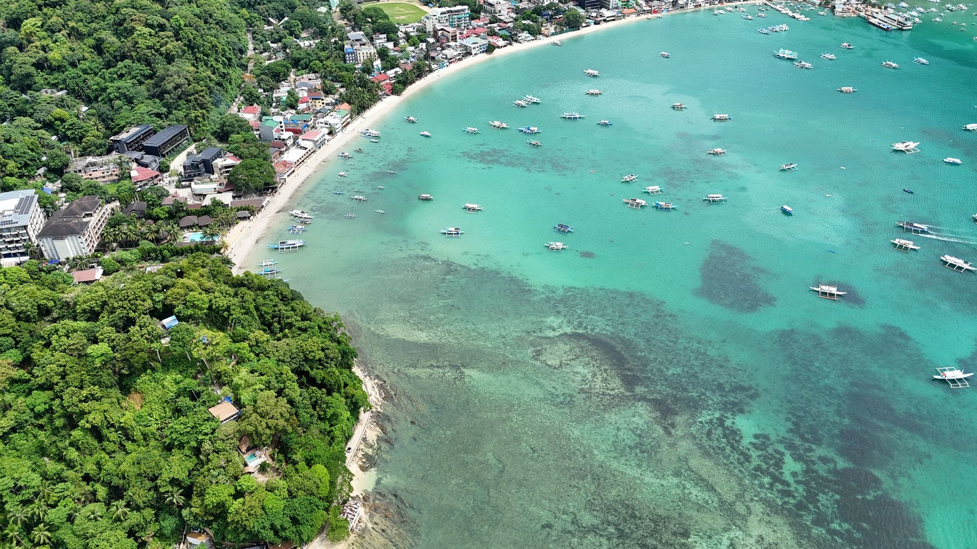An aerial view of a tropical beach with boats in the water.