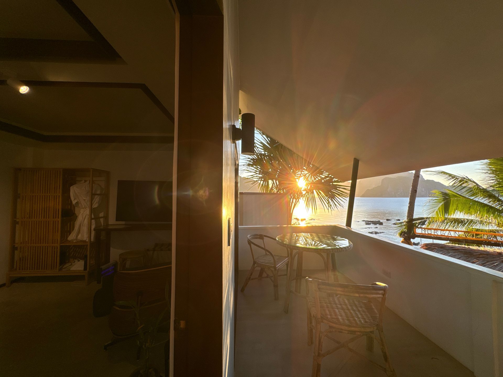 Room 2 The sun is setting over a balcony with tables and chairs.