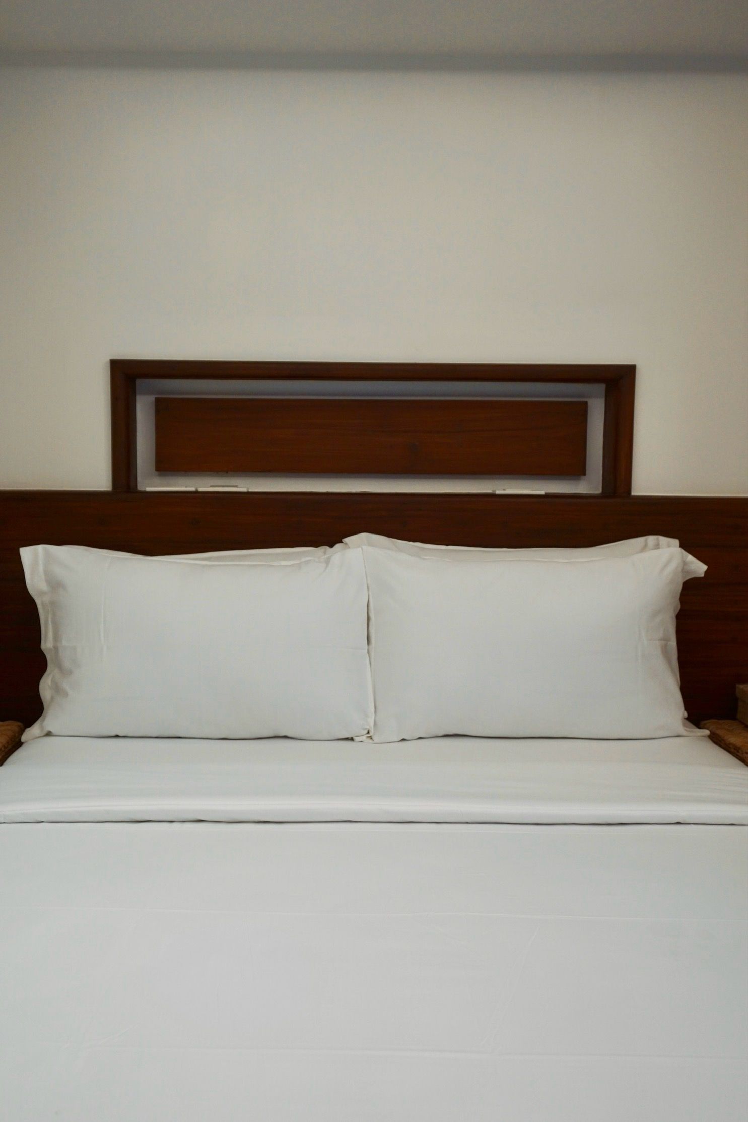 A bed with white sheets and pillows in a hotel room