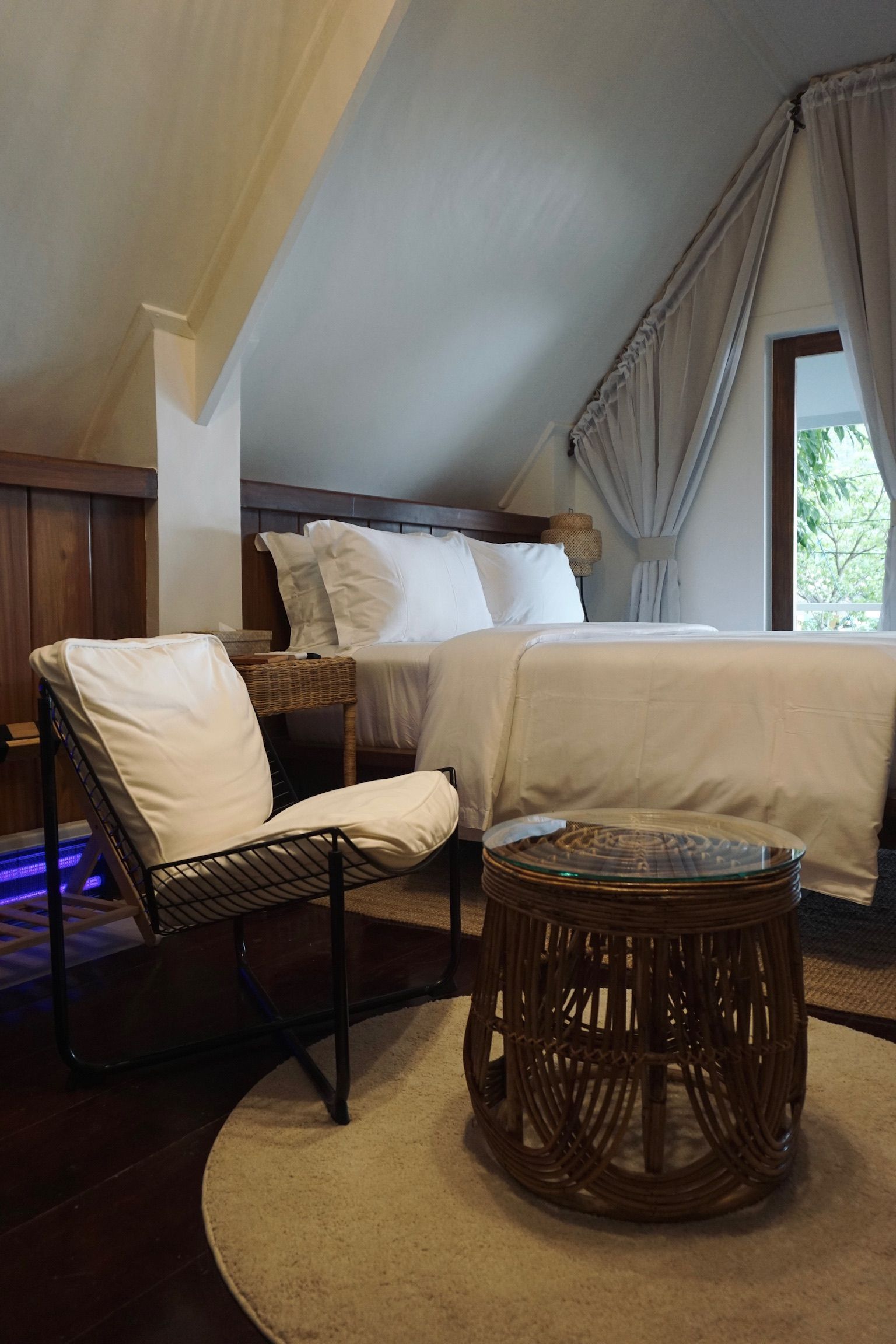 A bedroom with a bed , chair , table and window.