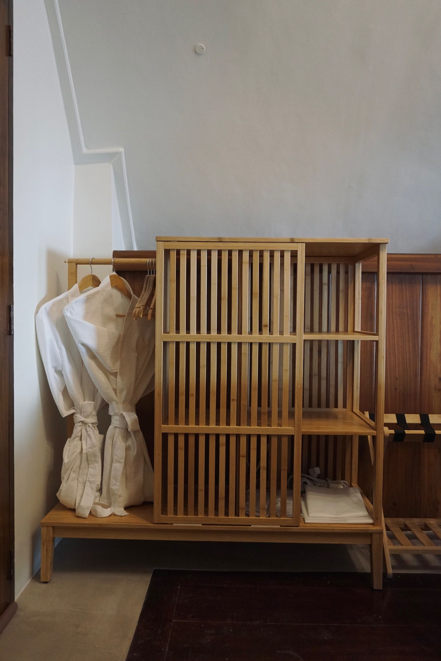 A wooden cage with clothes hanging on it in a room.