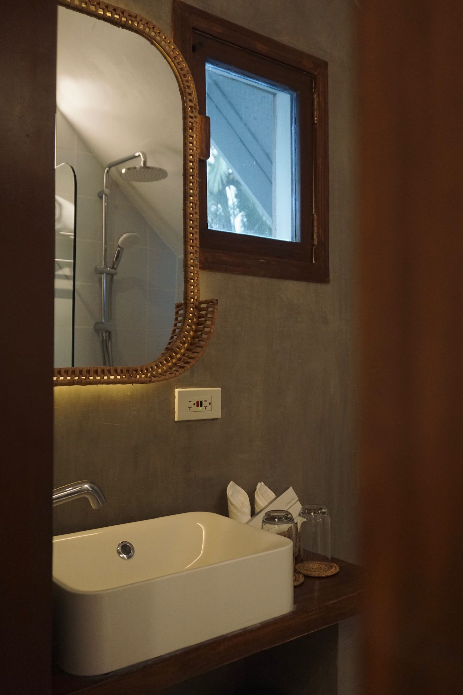 A bathroom with a sink , mirror and window.