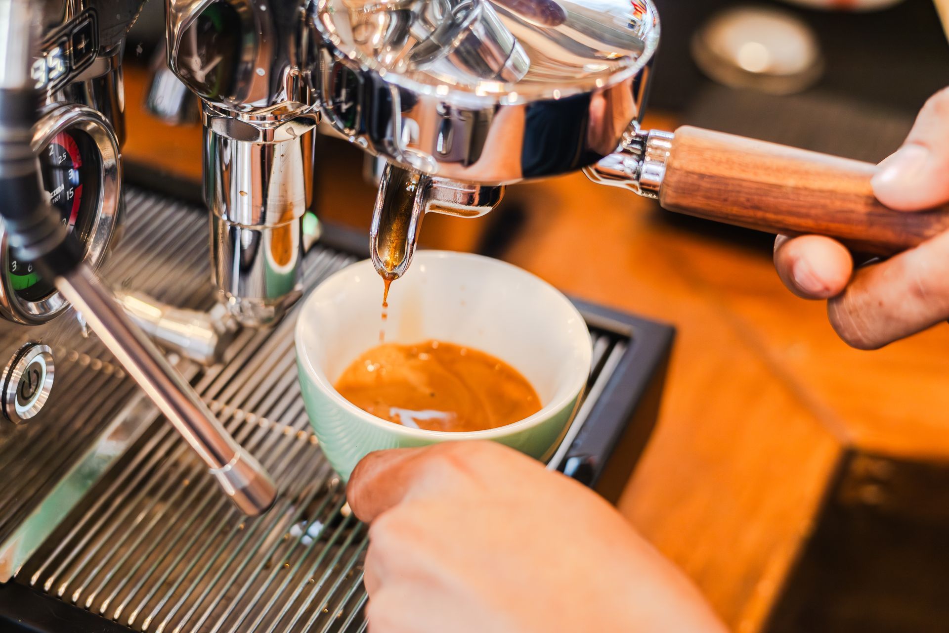 A person is pouring coffee into a cup from an espresso machine.