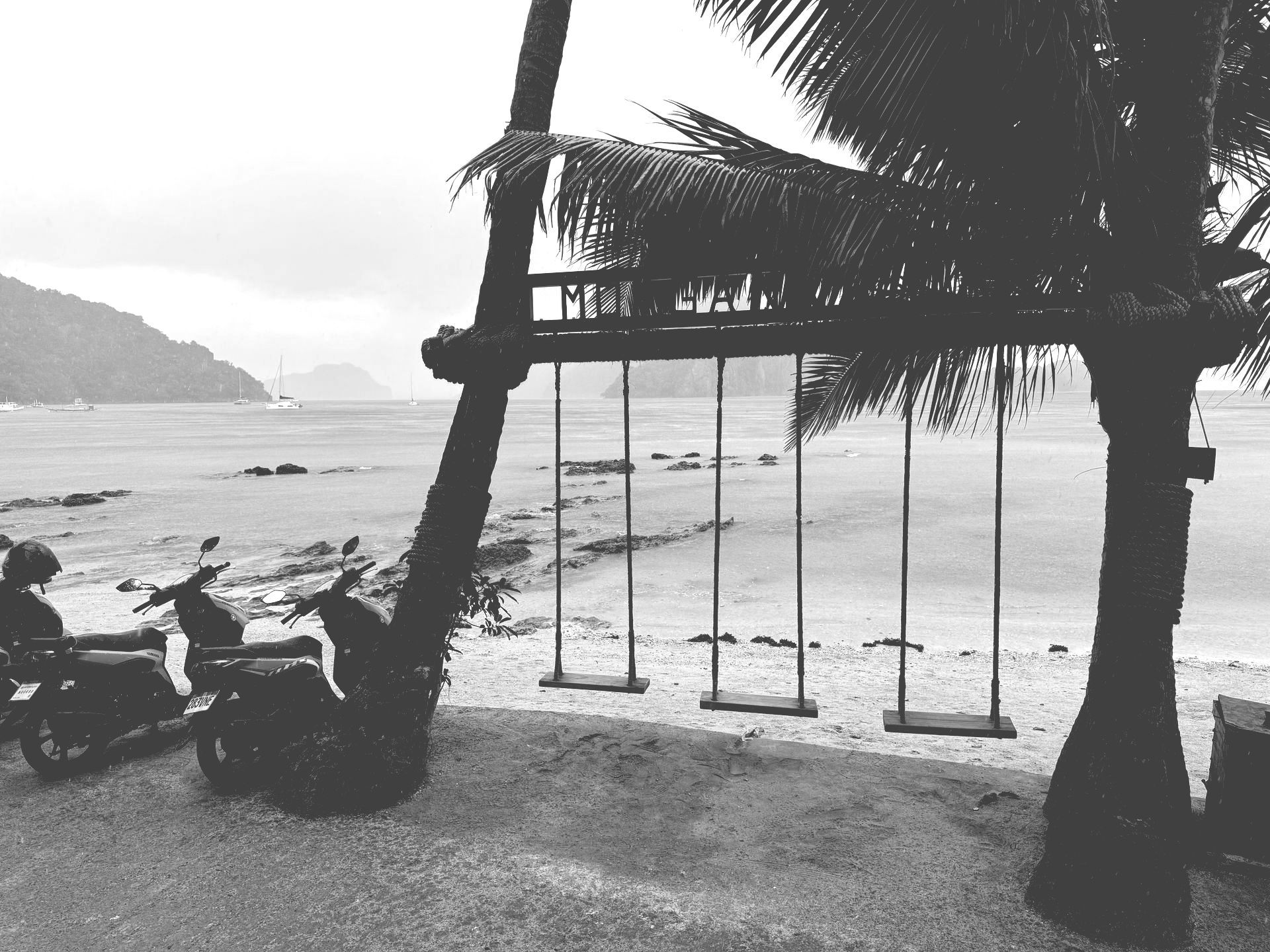 A black and white photo of swings on a beach