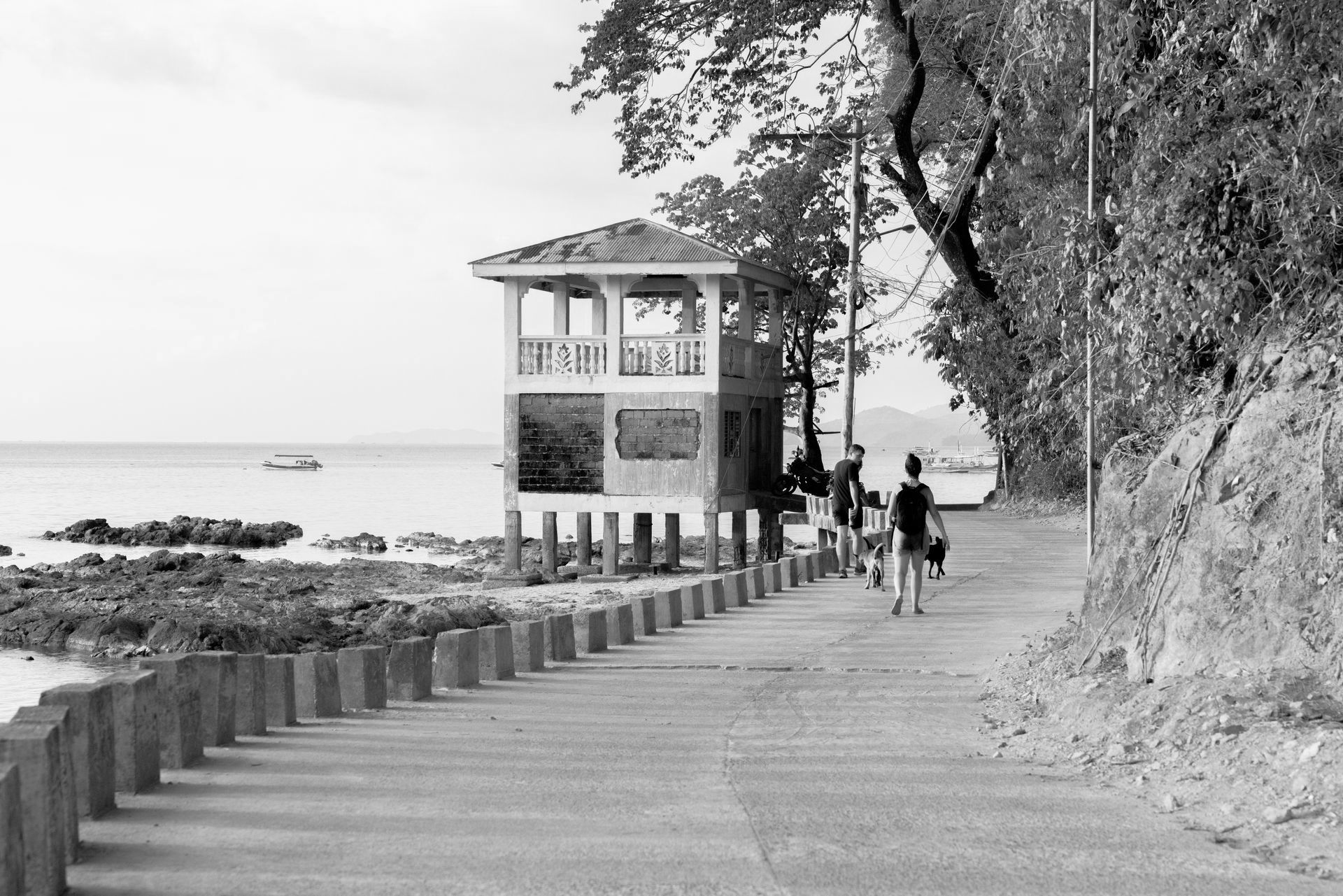 A black and white photo of people walking on a path near the ocean