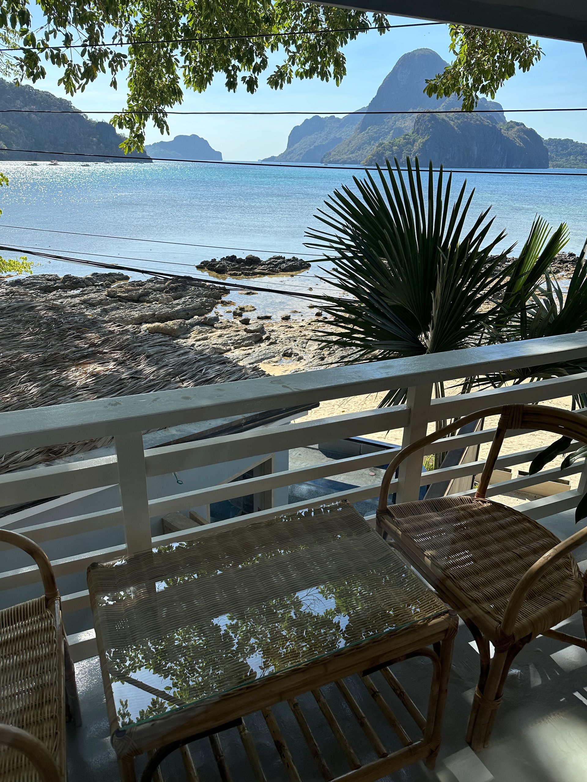 A view of the ocean from a balcony with a table and chairs.