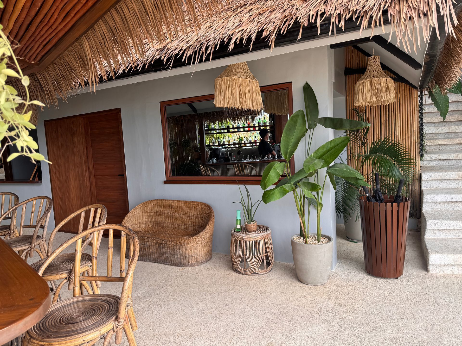 A room with a couch , chairs , tables and potted plants.