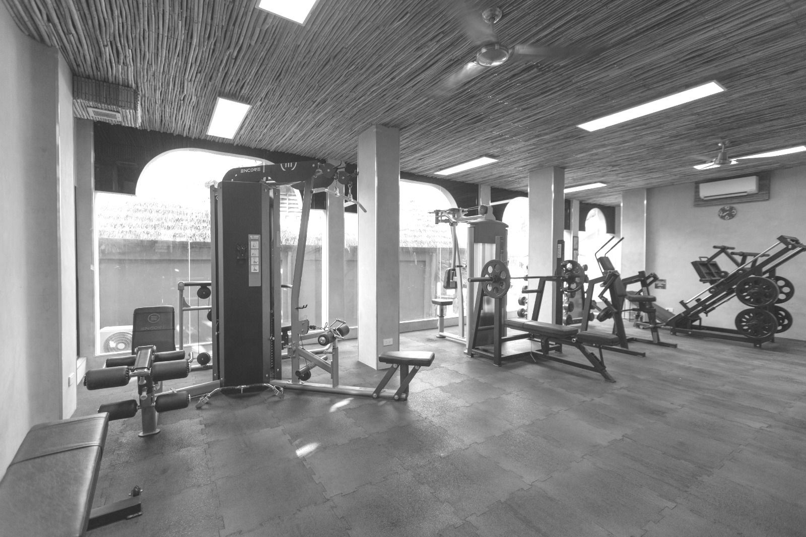 A black and white photo of a gym filled with lots of exercise equipment.