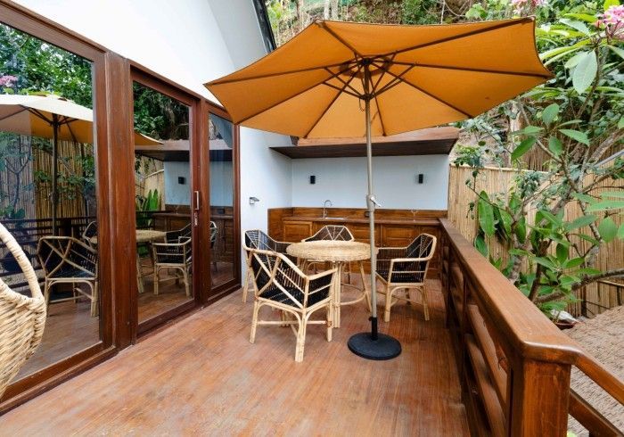 A wooden deck with a table and chairs and an umbrella.