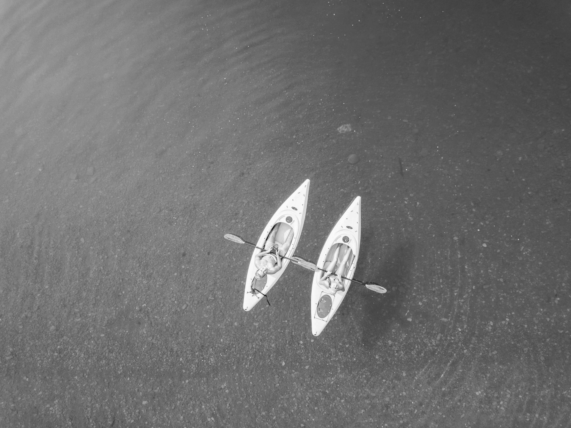A black and white photo of two kayaks in the water