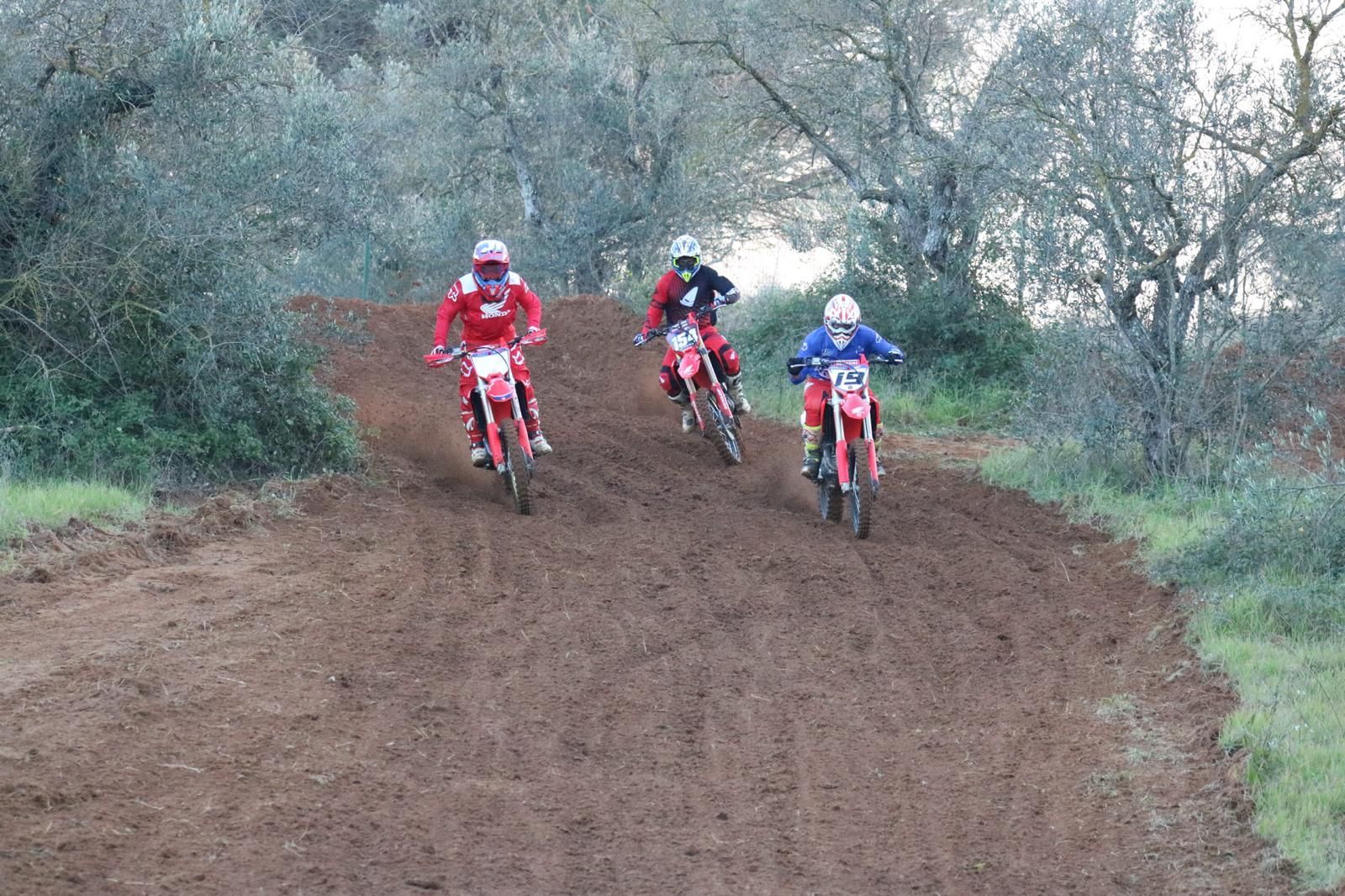 Pilota di motocross su una moto Honda rossa che salta sopra un cumulo di terra su una pista.