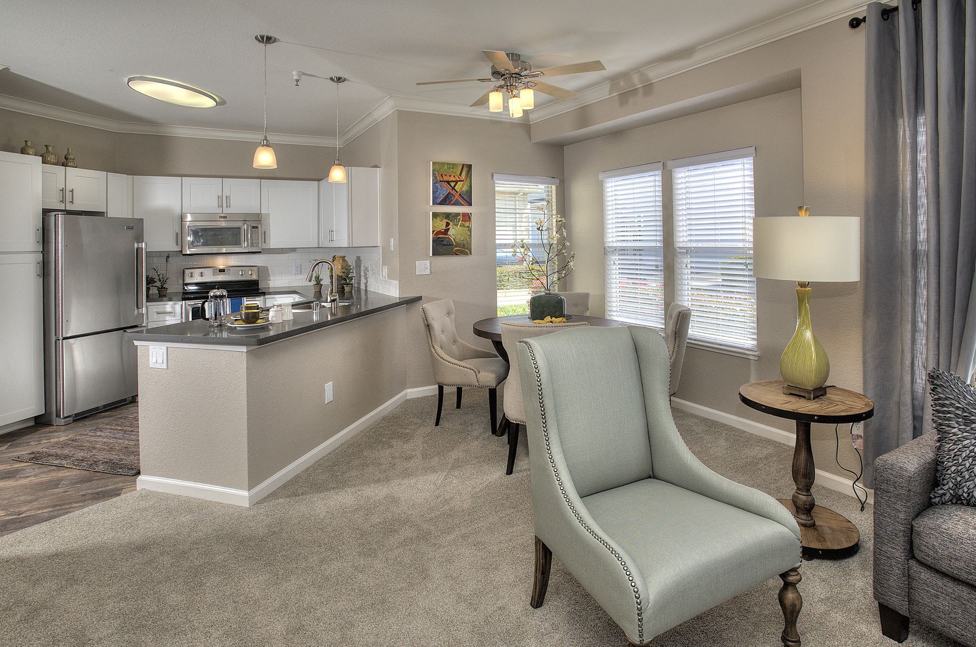 Open-concept apartment living space with kitchen island, white cabinets, and dining area