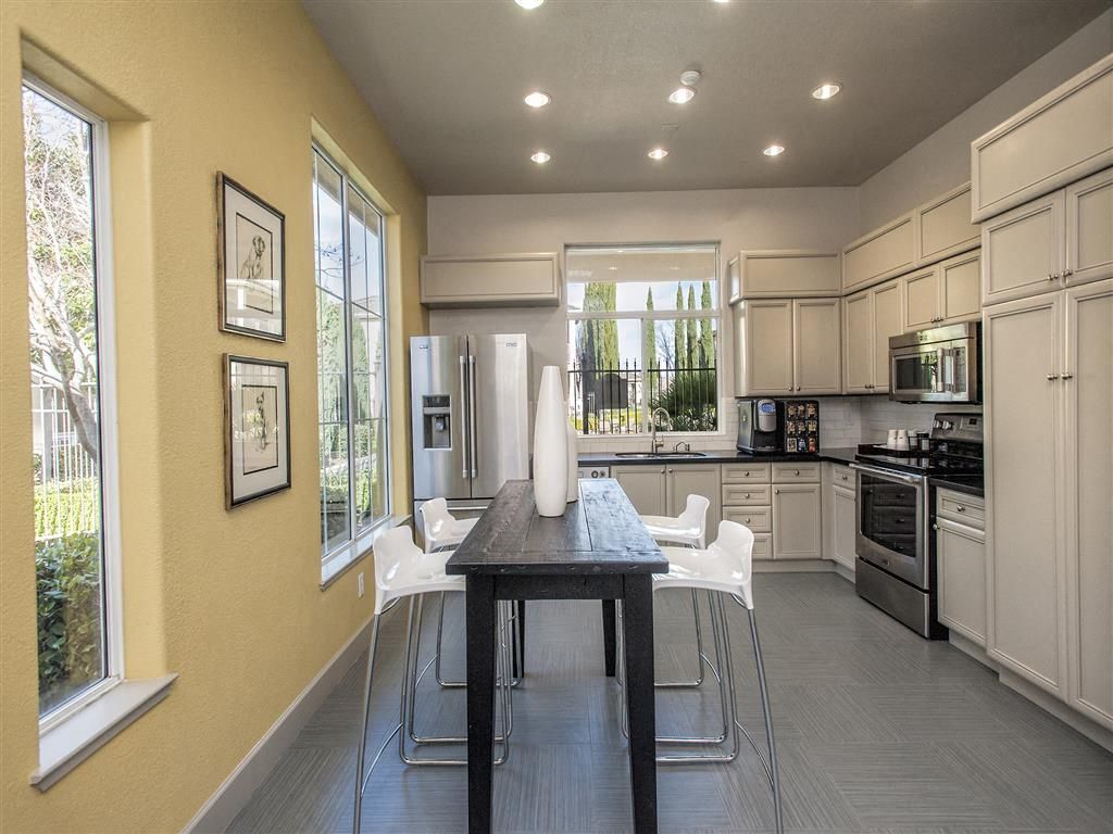 Modern kitchen in an apartment featuring white cabinets, stainless steel appliances, and a dark dining island.