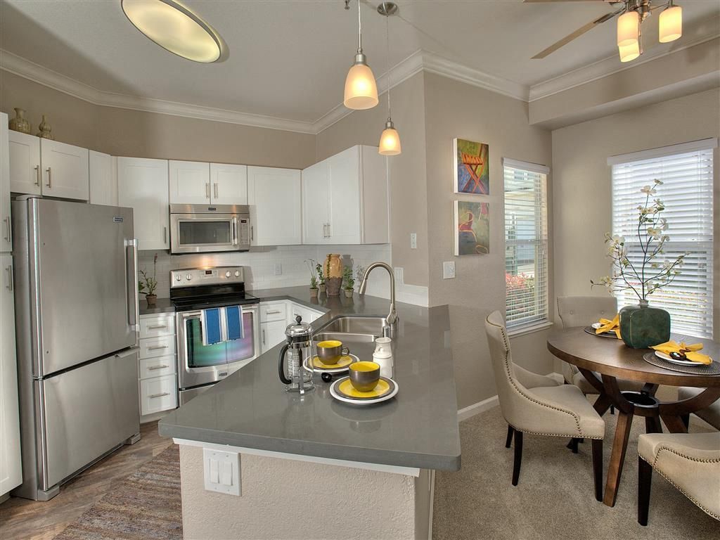Bright modern kitchen with white cabinets, stainless steel appliances, and a gray island.