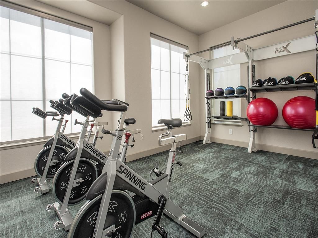 Fitness room with spin bikes, medicine balls, and a rack of equipment.
