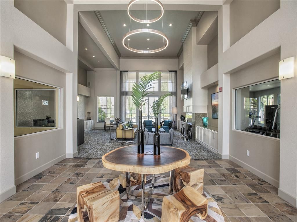 Modern multifamily lobby with a round wooden table centerpiece and lounge seating.