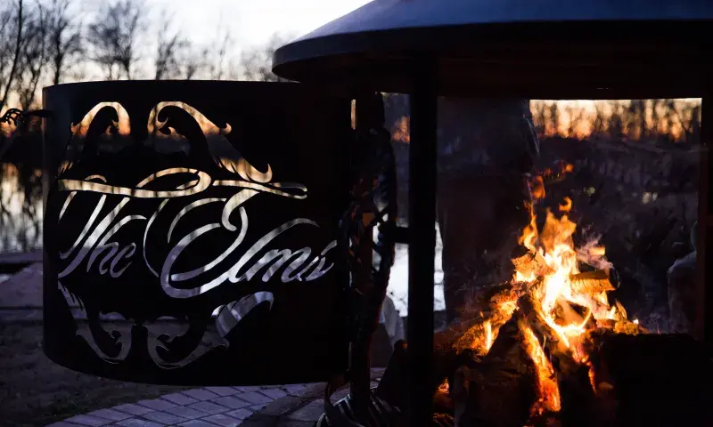 A fire burns inside a metal fire pit with the words 