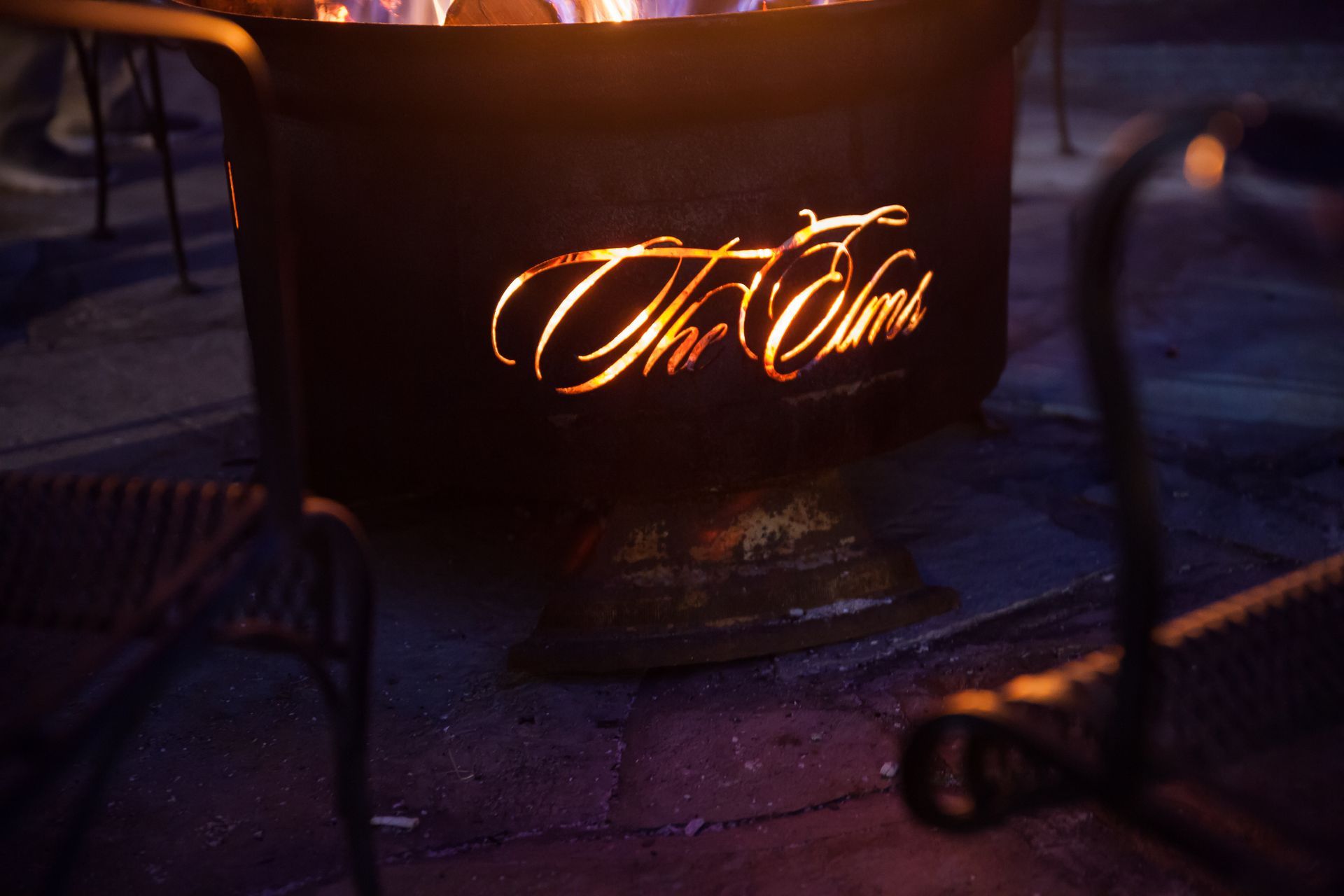 A black metal fire pit glows with the cut-out words 
