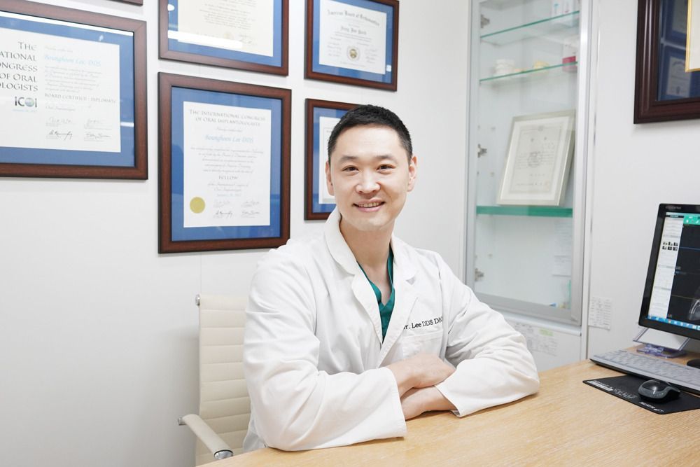 A man in a lab coat is sitting at a desk in front of a computer.
