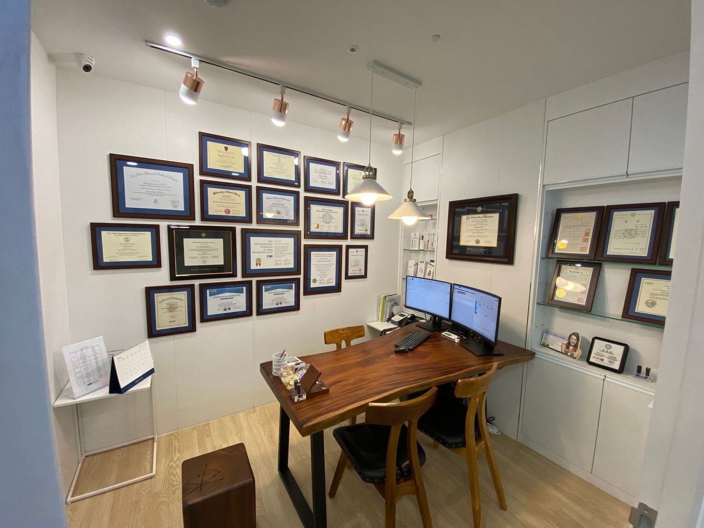 A conference room with a wooden table and chairs and a wall filled with certificates.