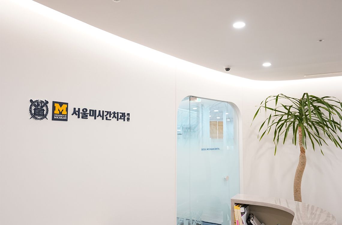 A white wall with a sign on it and a plant in front of it.