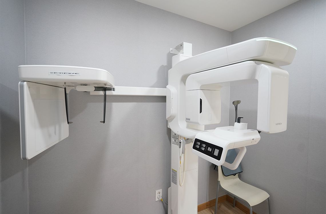 An x-ray machine is sitting in a room next to a chair.