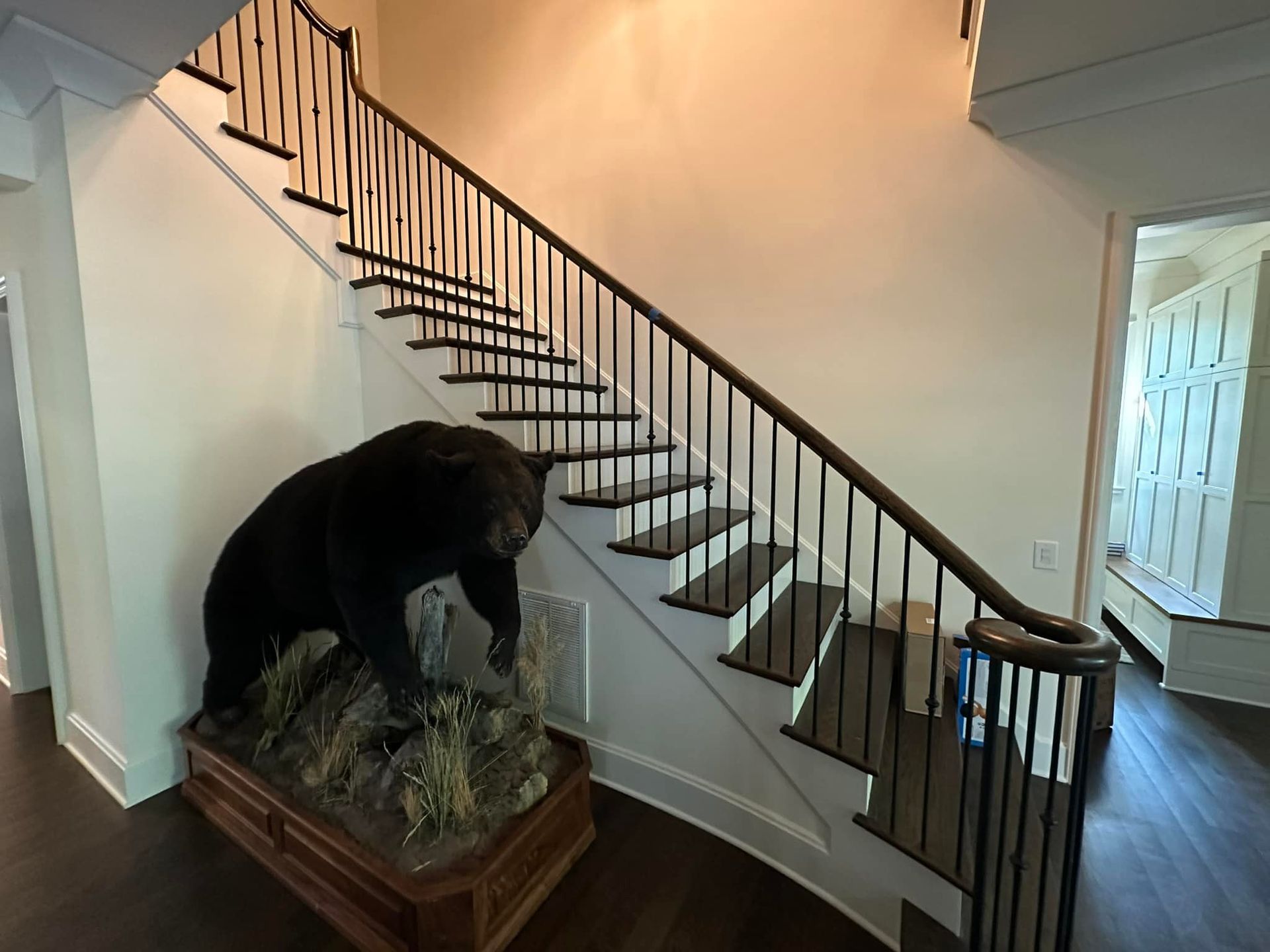Black bear taxidermy next to a staircase with dark wood steps and railing.