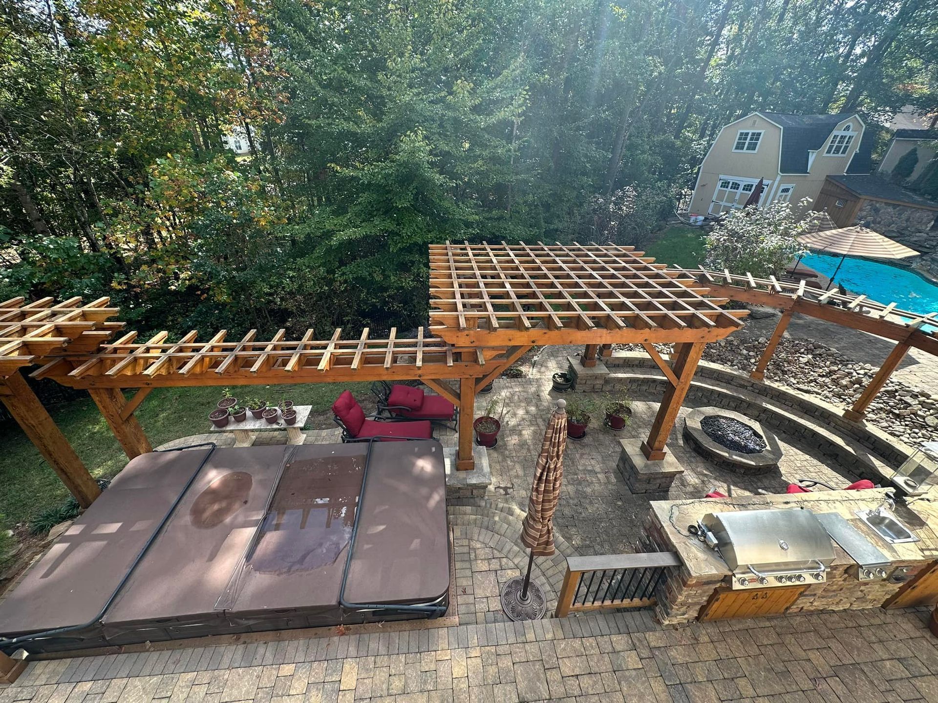 Backyard patio with hot tub, pergola, fire pit, outdoor kitchen, and pool.