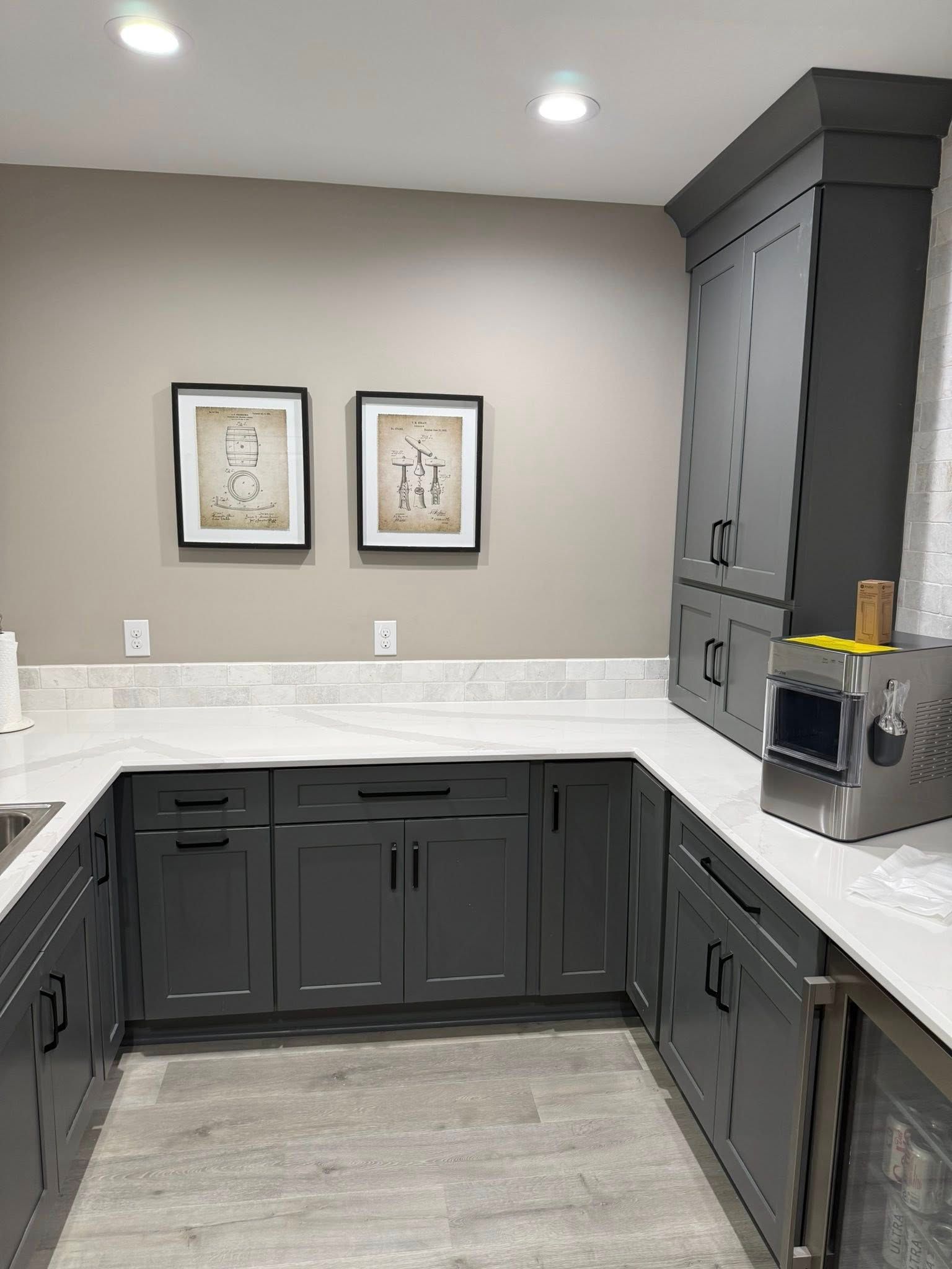 Gray kitchen cabinets and countertops in a u-shape layout. Two framed art pieces on the wall.
