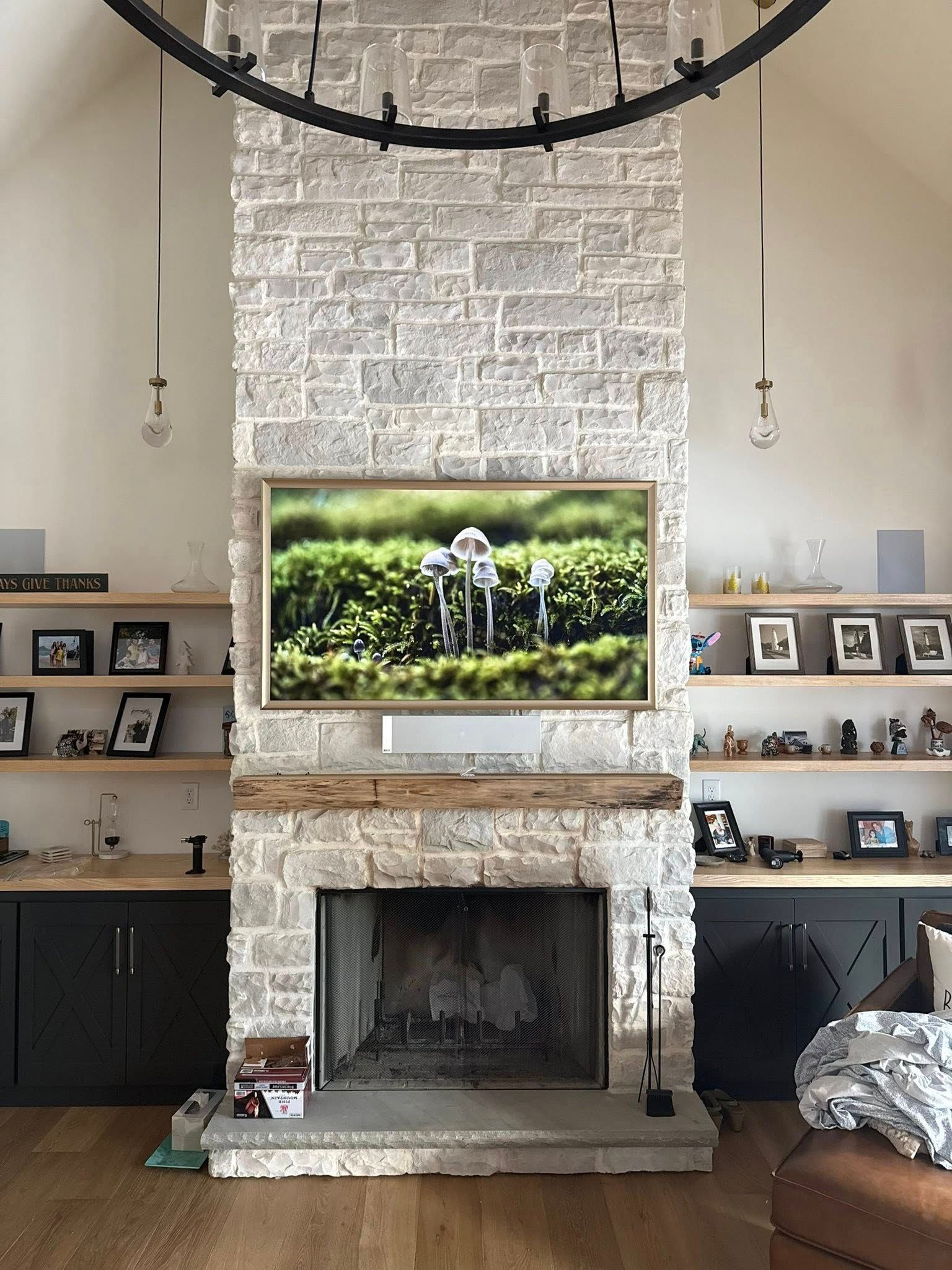Stone fireplace with built-in shelves and black cabinets. A TV is mounted above the fireplace.
