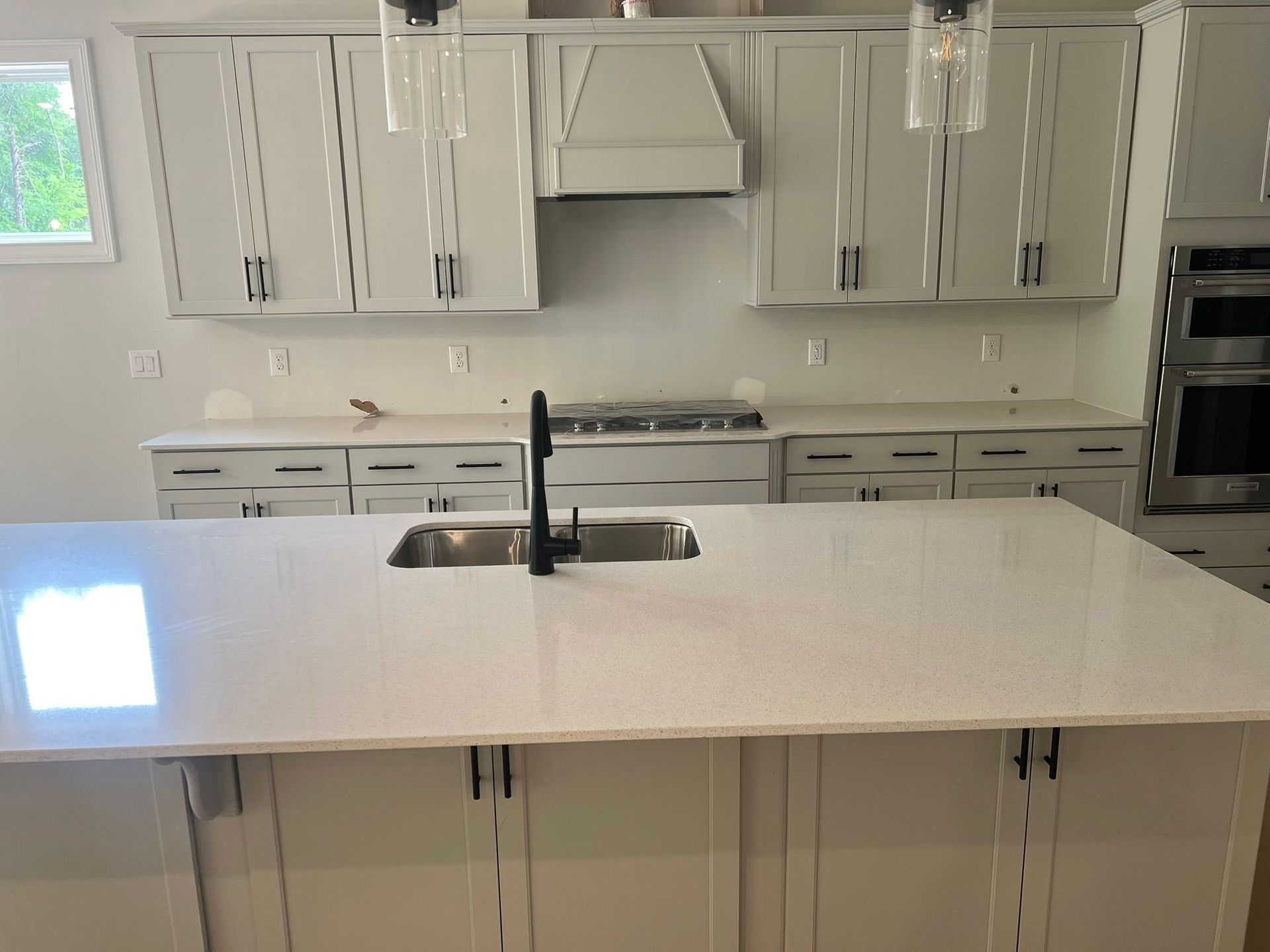 Modern kitchen with white cabinets, island, and countertops; stainless steel appliances.