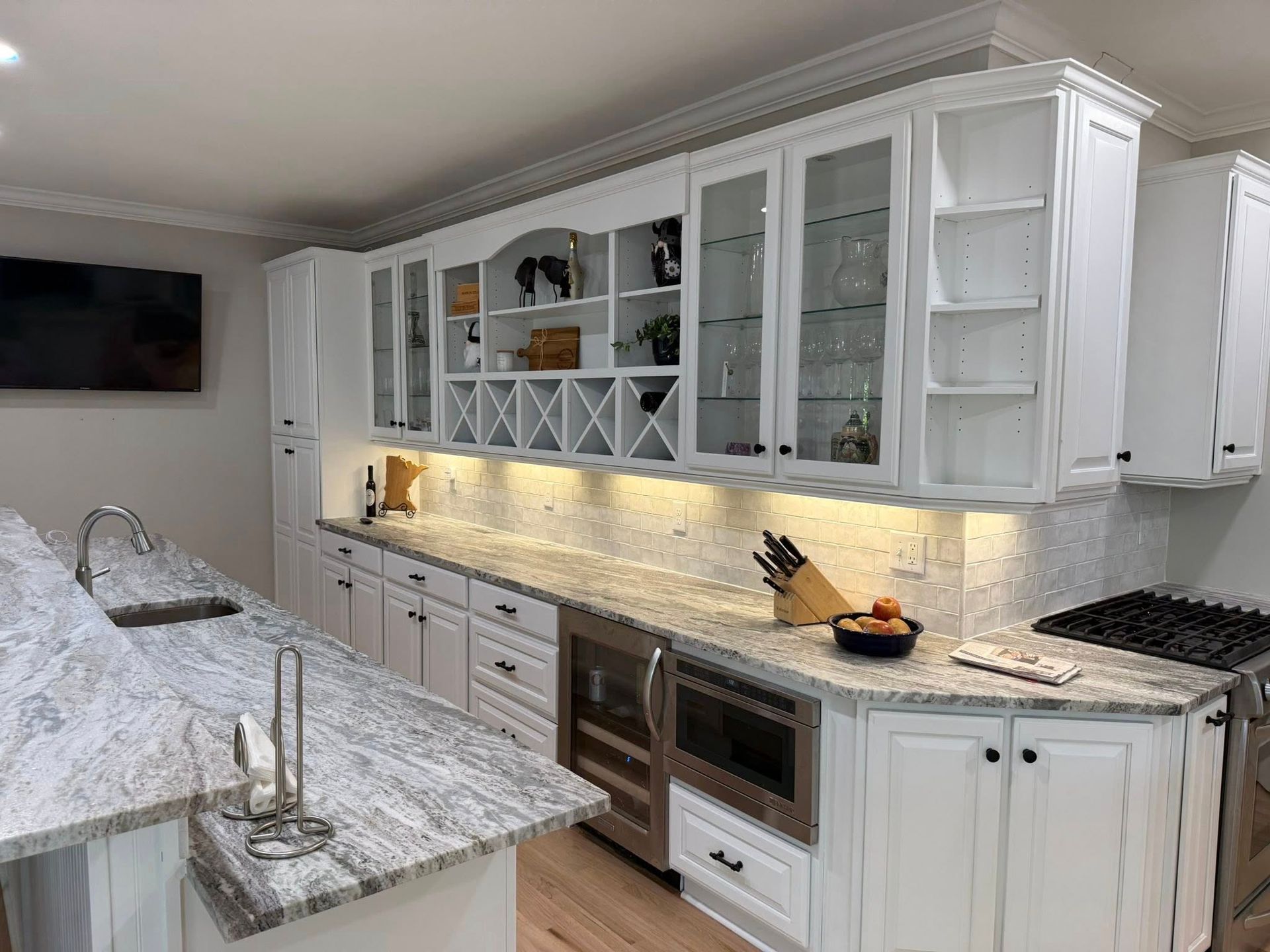 White kitchen with granite countertops, cabinets, wine rack, and built-in appliances.