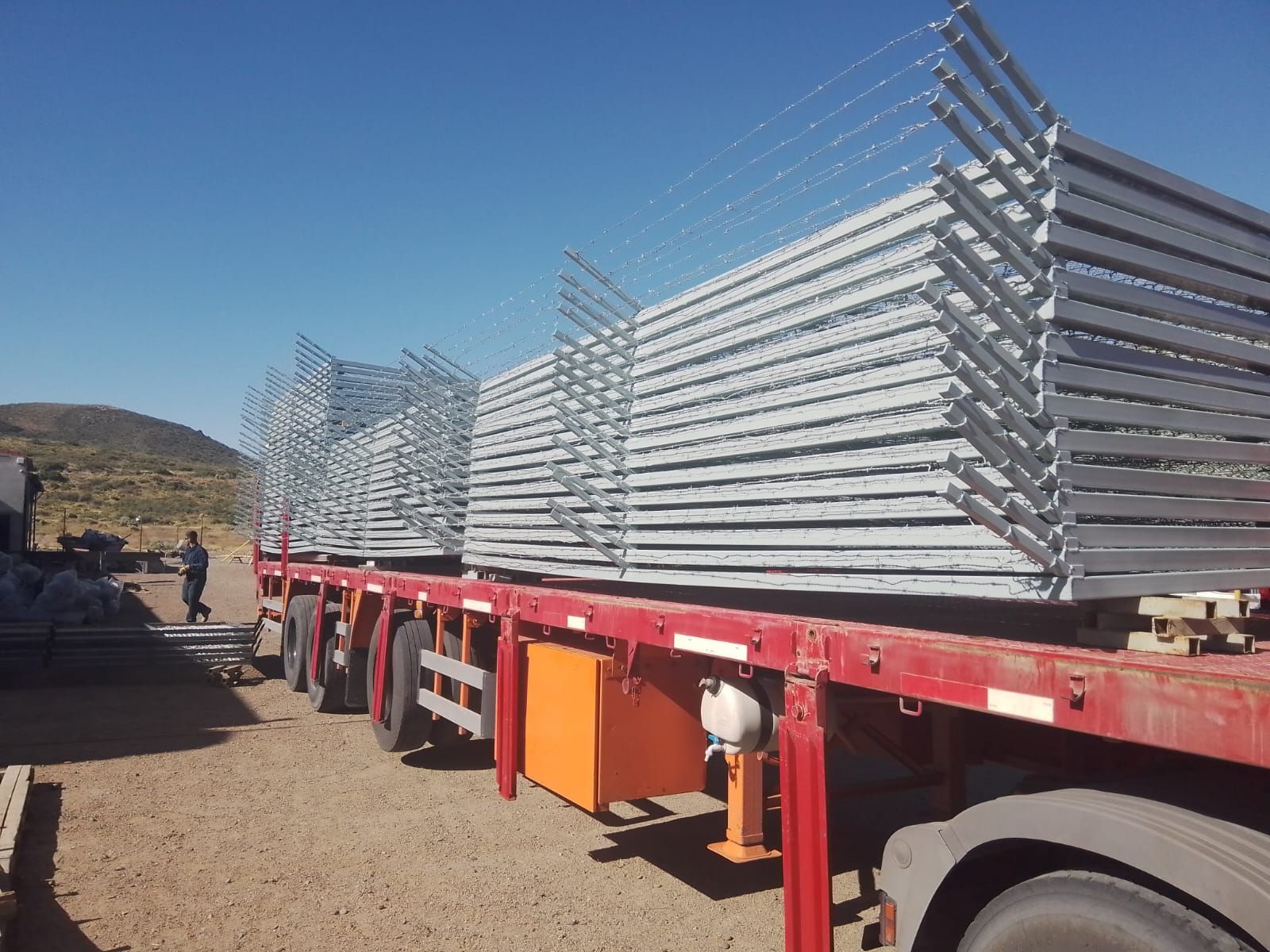 Camión cargado con paneles metálicos apilados, al aire libre bajo un cielo azul.