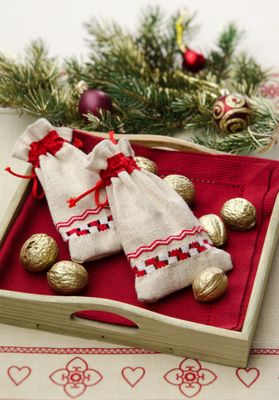 A wooden tray with two bags of nuts and a christmas tree in the background