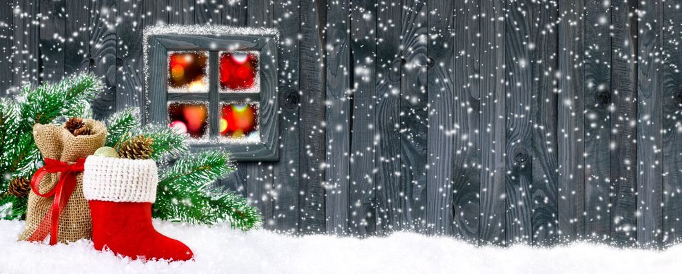 A christmas stocking is sitting in the snow in front of a wooden wall.