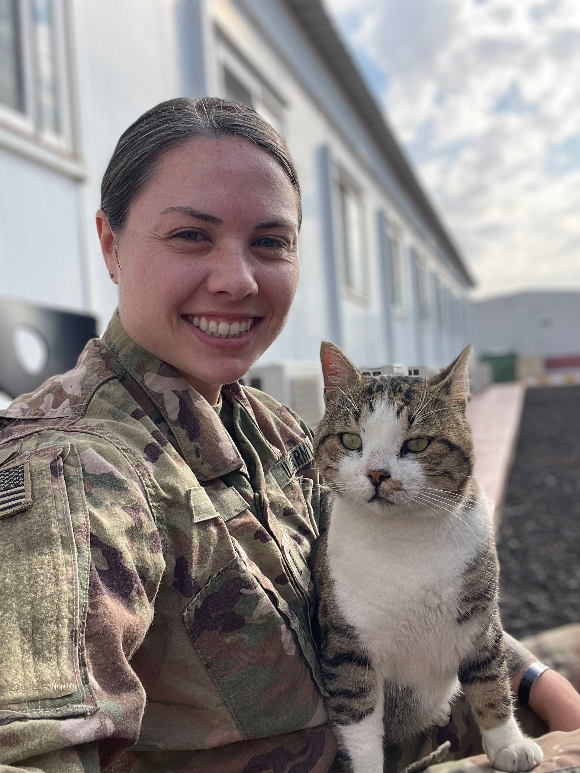 A woman in a military uniform is holding a cat