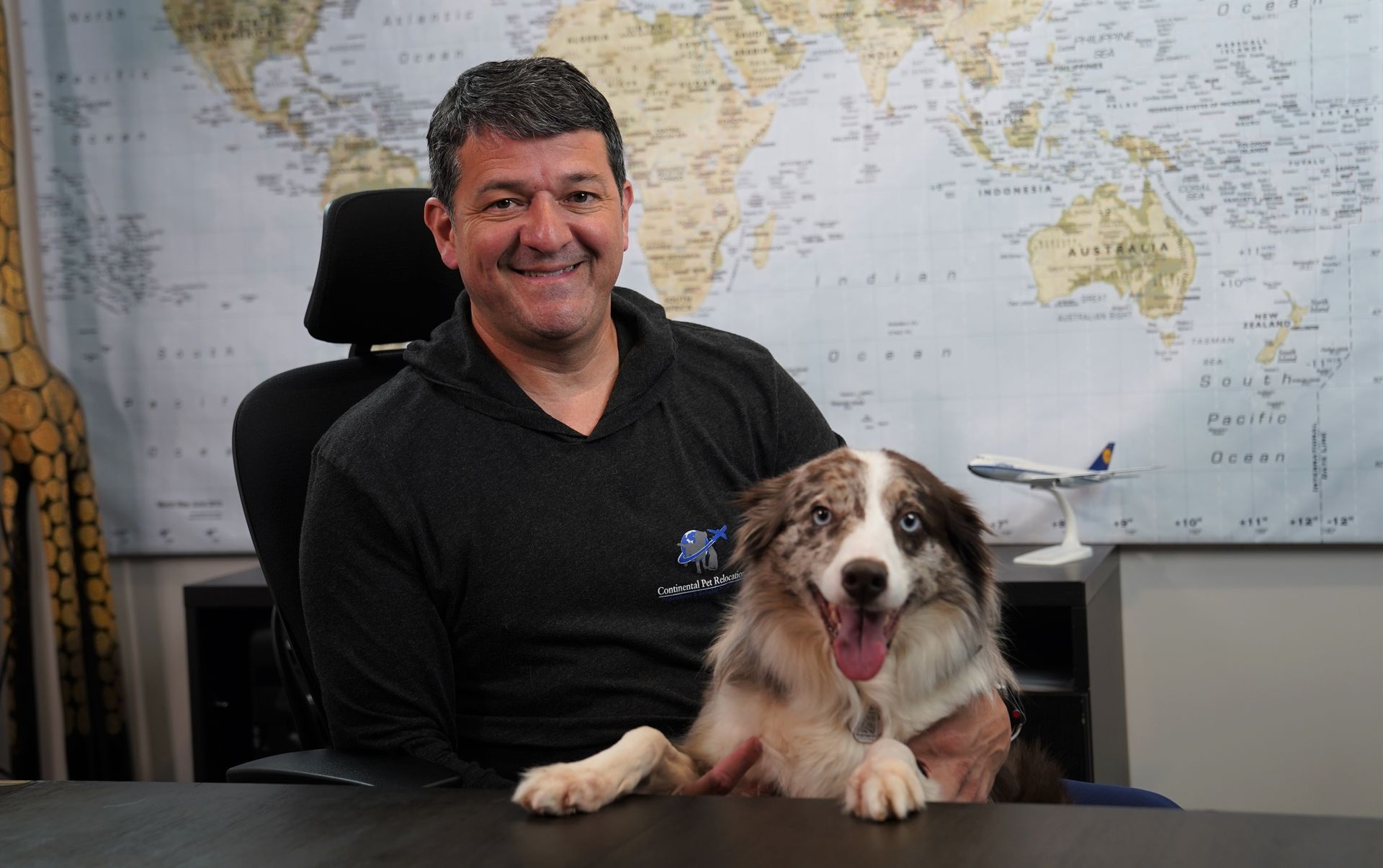 A man is sitting at a desk holding a dog.