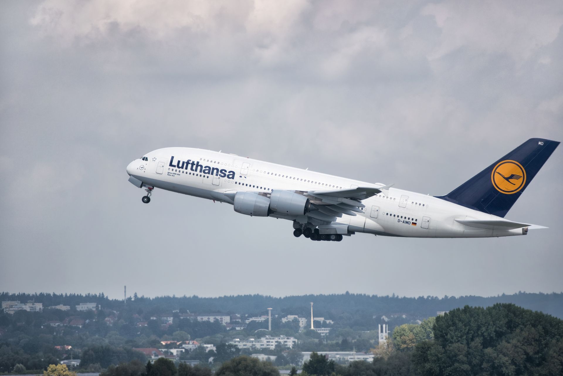 A lufthansa jumbo jet is taking off from an airport runway.